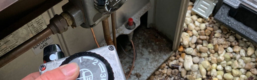 Hand adjusting the control dial on a natural gas hot water unit