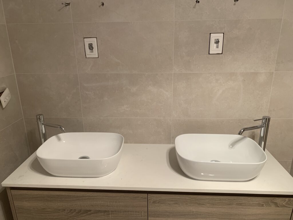 Twin above-counter basins and chrome tapware in a renovated bathroom